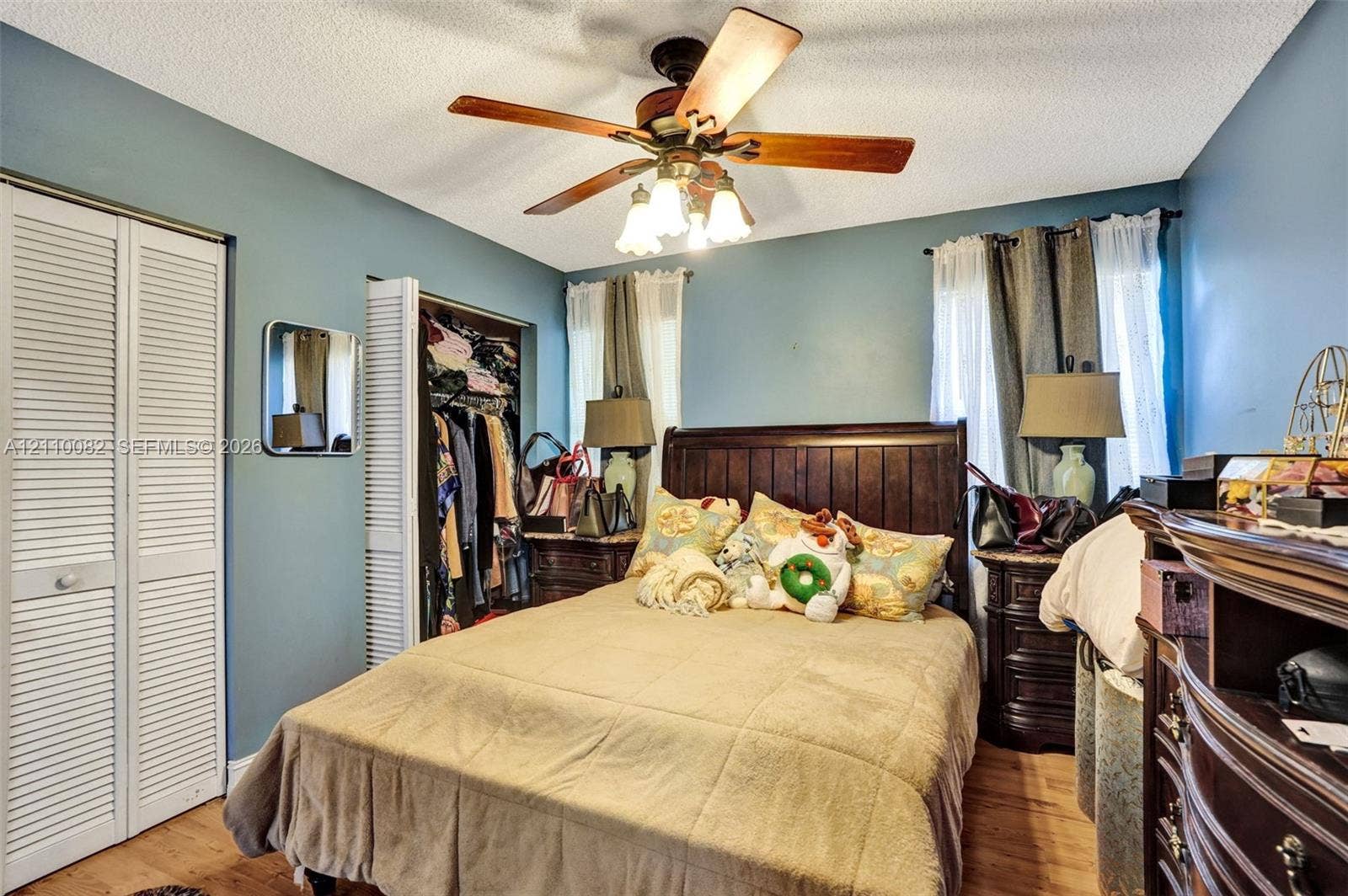 Room featuring wood-finish flooring, dual bi-fold closet doors, and a ceiling fan with integrated light fixture