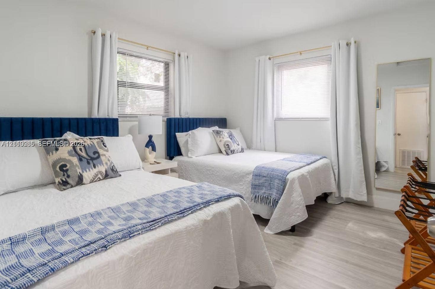 7815 NW 5th Court, #1, Miami, Miami, FL 33150 Neutral-toned interior featuring wood-finish flooring, two blue upholstered headboards, and dual windows with natural light
