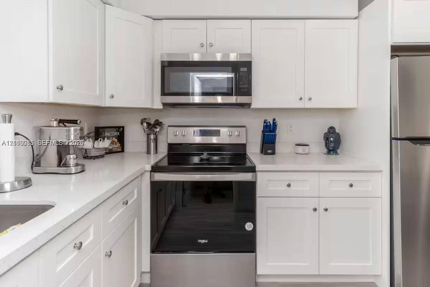 7815 NW 5th Court, #1, Miami, Miami, FL 33150 Kitchen featuring white shaker-style cabinetry, solid-surface countertops, and a full suite of stainless steel appliances, including an over-the-range microwave and a smooth-top range