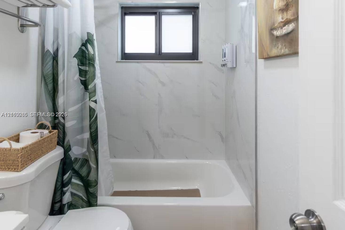 7815 NW 5th Court, #1, Miami, Miami, FL 33150 Full-height shower surround featuring large-format stone-pattern tile, white porcelain soaking tub, horizontal sliding window, and chrome wall-mounted towel rack