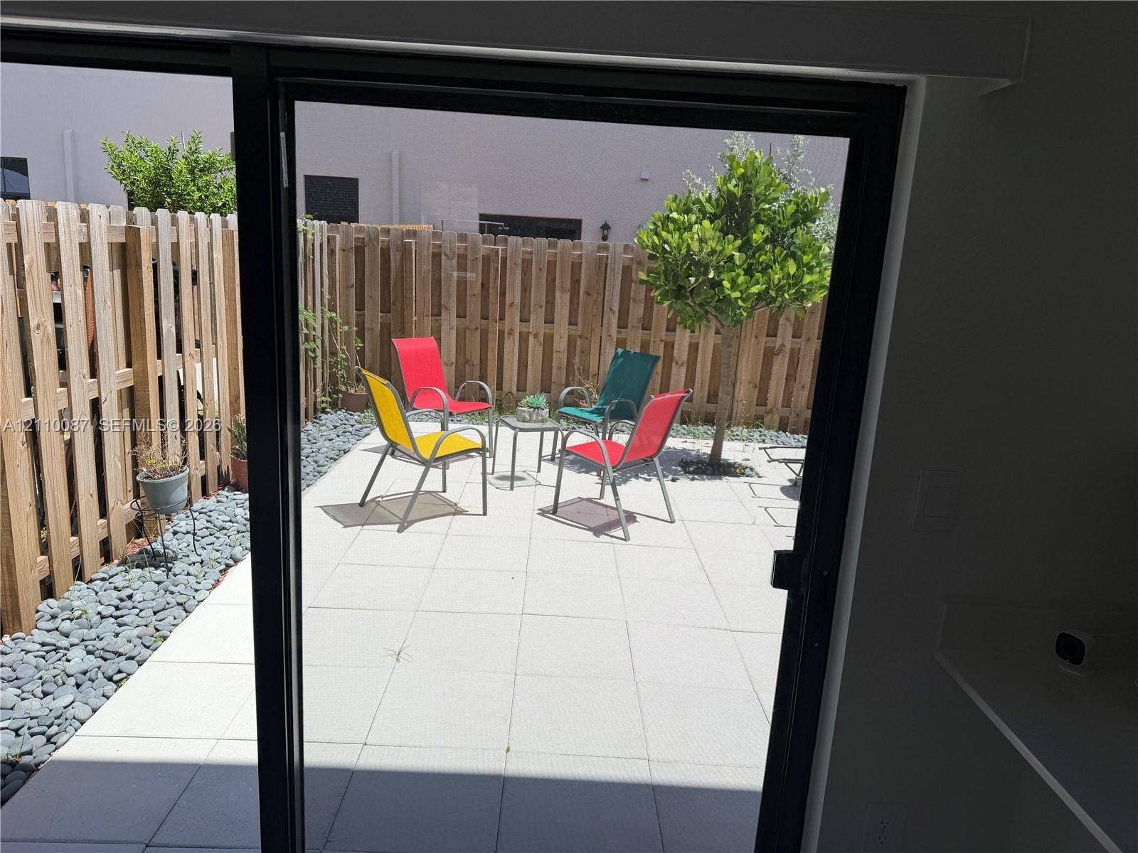 1358 NE 3rd Avenue, #1, Florida City, Florida City, FL 33034 Private outdoor patio featuring light-toned concrete pavers, stone gravel borders, and a vertical wood-plank privacy fence