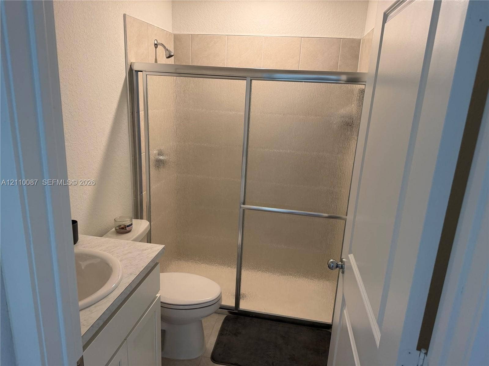 1358 NE 3rd Avenue, #1, Florida City, Florida City, FL 33034 Bathroom featuring a vanity with a stone-finish countertop and integrated sink, a walk-in shower with a sliding glass door, and neutral tile wall surround