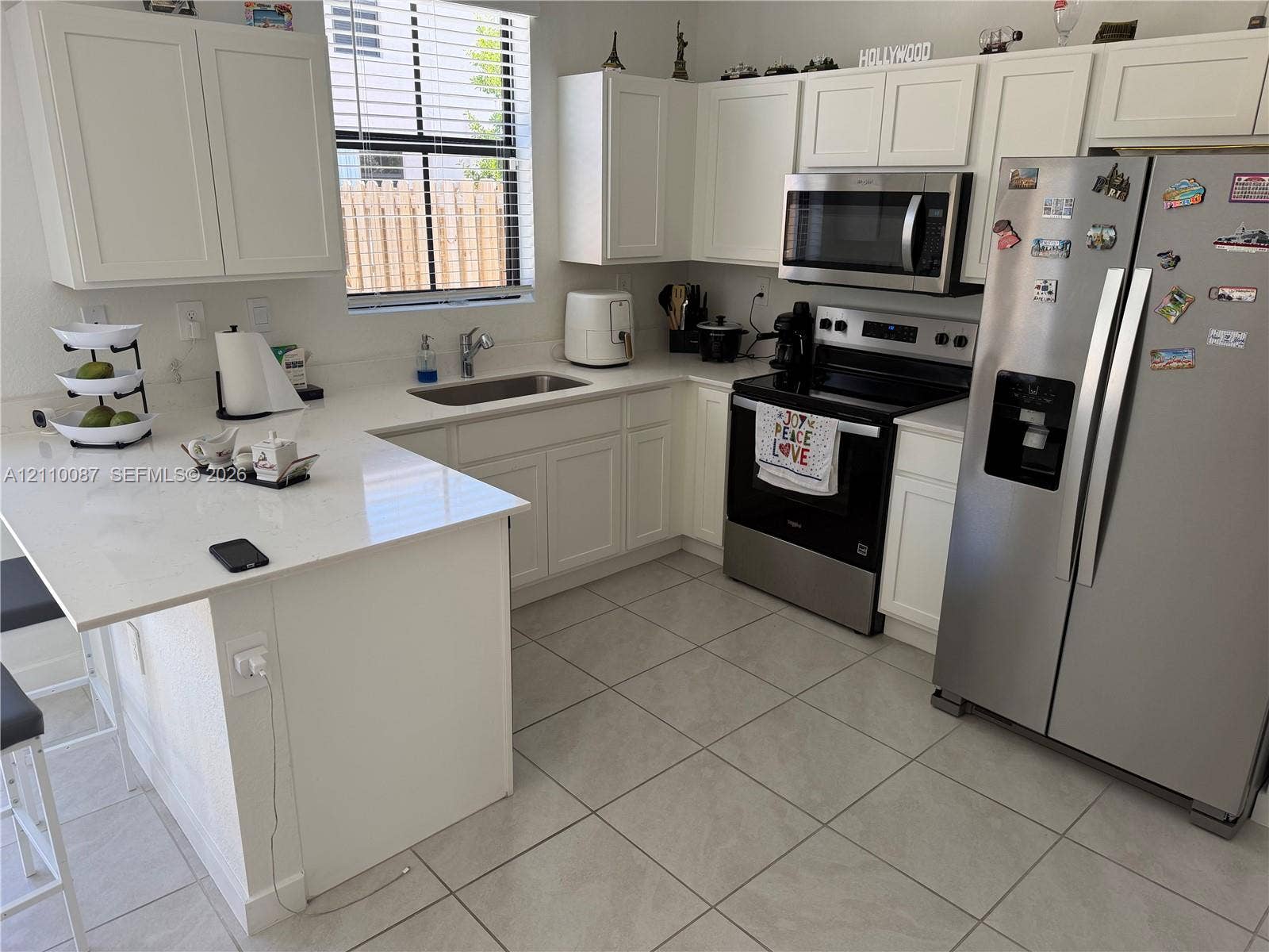 1358 NE 3rd Avenue, #1, Florida City, Florida City, FL 33034 Kitchen featuring white shaker-style cabinetry, white countertops with an integrated breakfast bar, stainless steel appliances, and tile flooring
