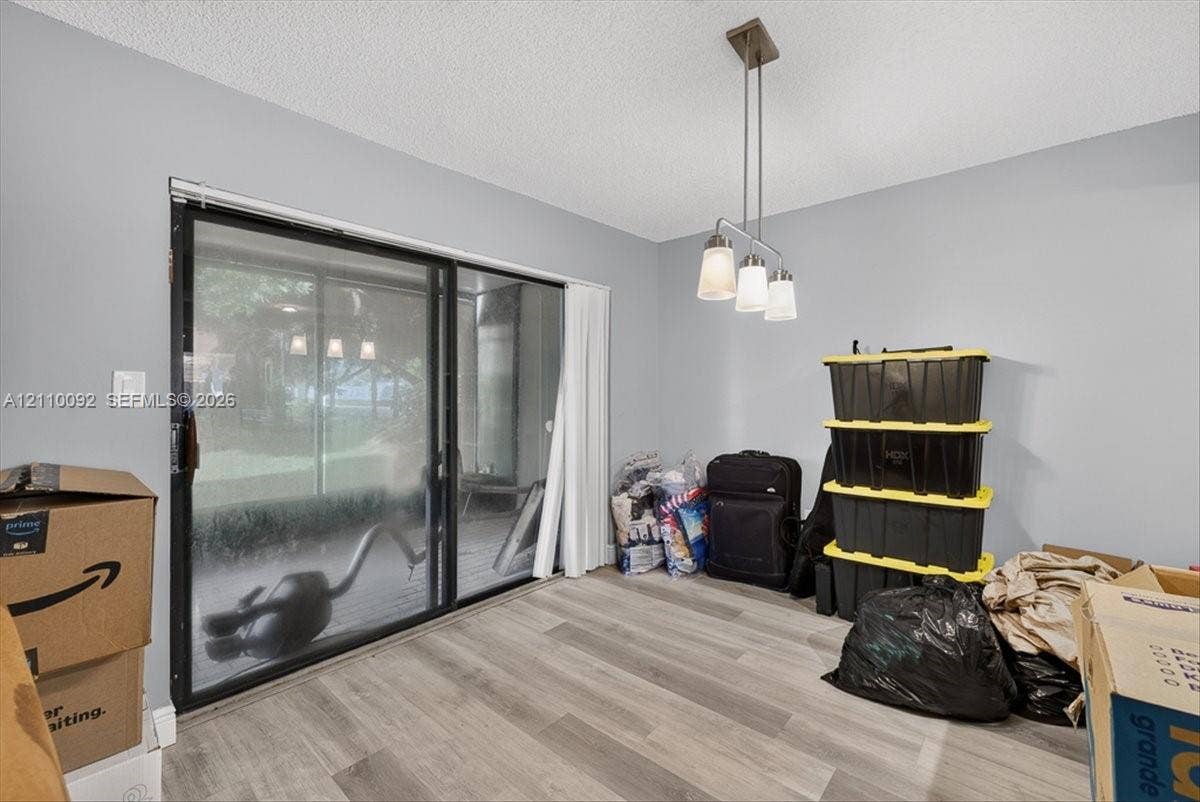 1403 SW 110th Way, Davie, FL 33324 Sliding glass door leading to a screened enclosure, wood-finish flooring, and a three-light pendant fixture