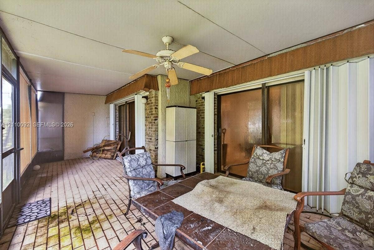 1403 SW 110th Way, Davie, FL 33324 Enclosed sunroom featuring brick flooring, brick exterior wall accents, a ceiling fan, and sliding glass door access