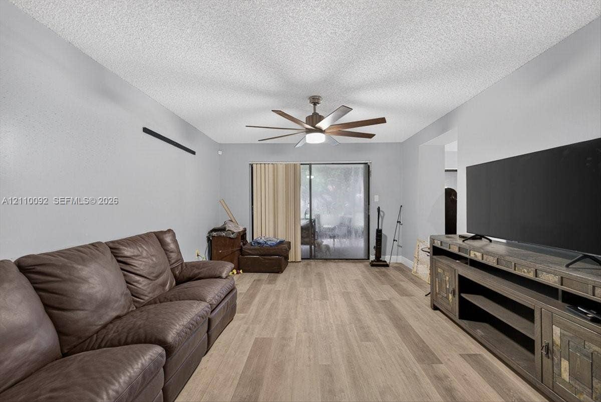 1403 SW 110th Way, Davie, FL 33324 Wood-finish flooring, multi-blade ceiling fan with integrated lighting, and glass sliding door