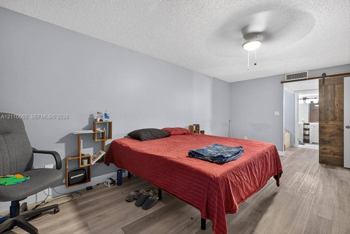 1403 SW 110th Way, Davie, FL 33324 Room featuring wood-finish flooring, a sliding barn-style door, and a ceiling-mounted light fixture