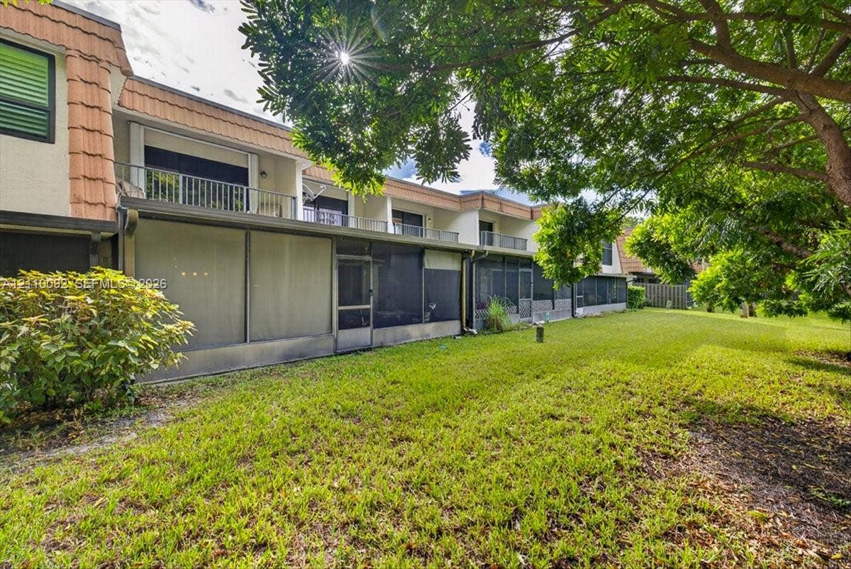 1403 SW 110th Way, Davie, FL 33324 Backyard featuring a grass lawn, screened-in ground-level patio, upper-level balconies with metal railings, and tile roof detailing