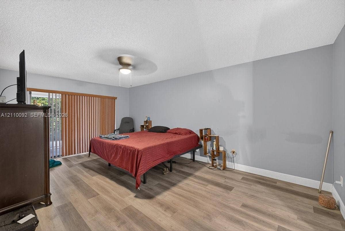 1403 SW 110th Way, Davie, FL 33324 Room featuring wood-finish flooring, a ceiling fan with integrated lighting, and vertical blinds covering the sliding glass door