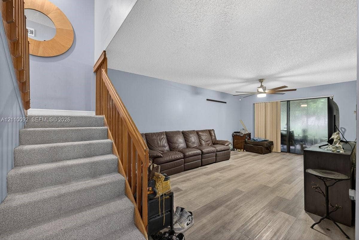 1403 SW 110th Way, Davie, FL 33324 Staircase with wood-finish railings and carpeted treads, wood-finish flooring, ceiling fan with integrated lighting, and sliding glass doors