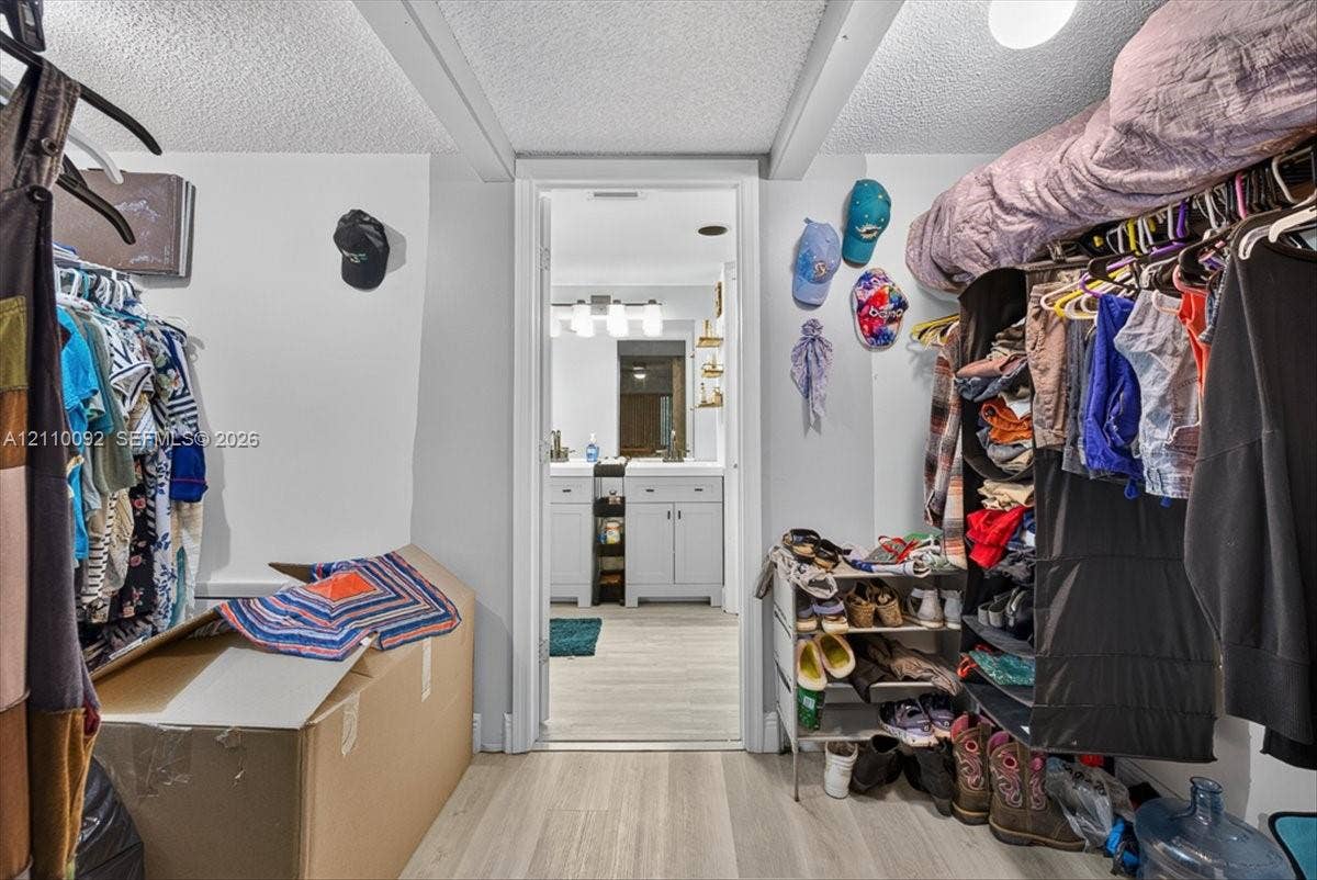 1403 SW 110th Way, Davie, FL 33324 Walk-in closet featuring tiered clothing rods and integrated upper shelving, with light-toned wood-finish flooring