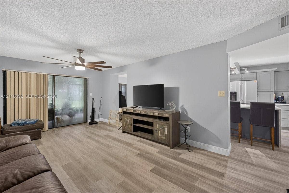 1403 SW 110th Way, Davie, FL 33324 Living space featuring wood-finish flooring, a multi-blade ceiling fan, and large glass sliding doors