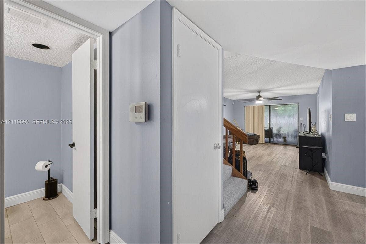 1403 SW 110th Way, Davie, FL 33324 Interior hall featuring wood-finish flooring, staircase with carpeted treads and wooden handrail, and sliding glass door