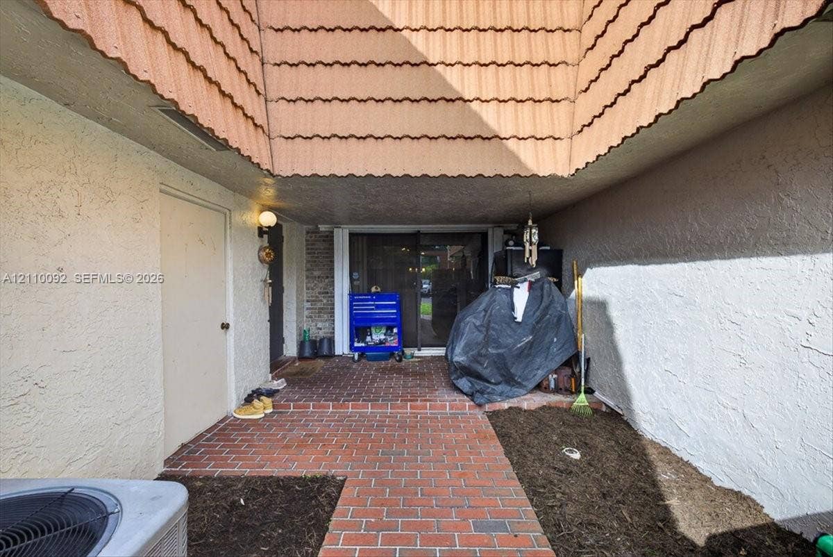 1403 SW 110th Way, Davie, FL 33324 Enclosed courtyard featuring brick flooring, stucco exterior walls, and overhead architectural detailing