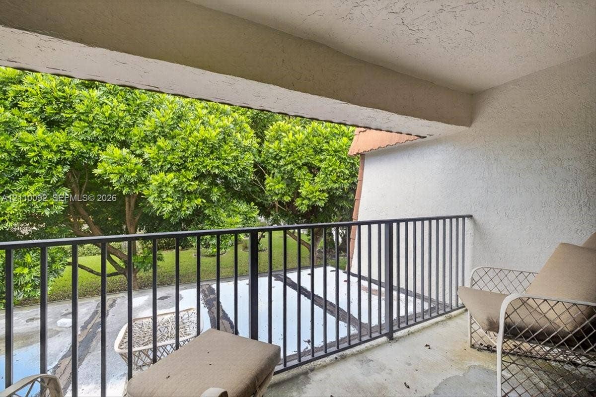 1403 SW 110th Way, Davie, FL 33324 Covered balcony featuring concrete flooring, textured walls, and a black metal railing