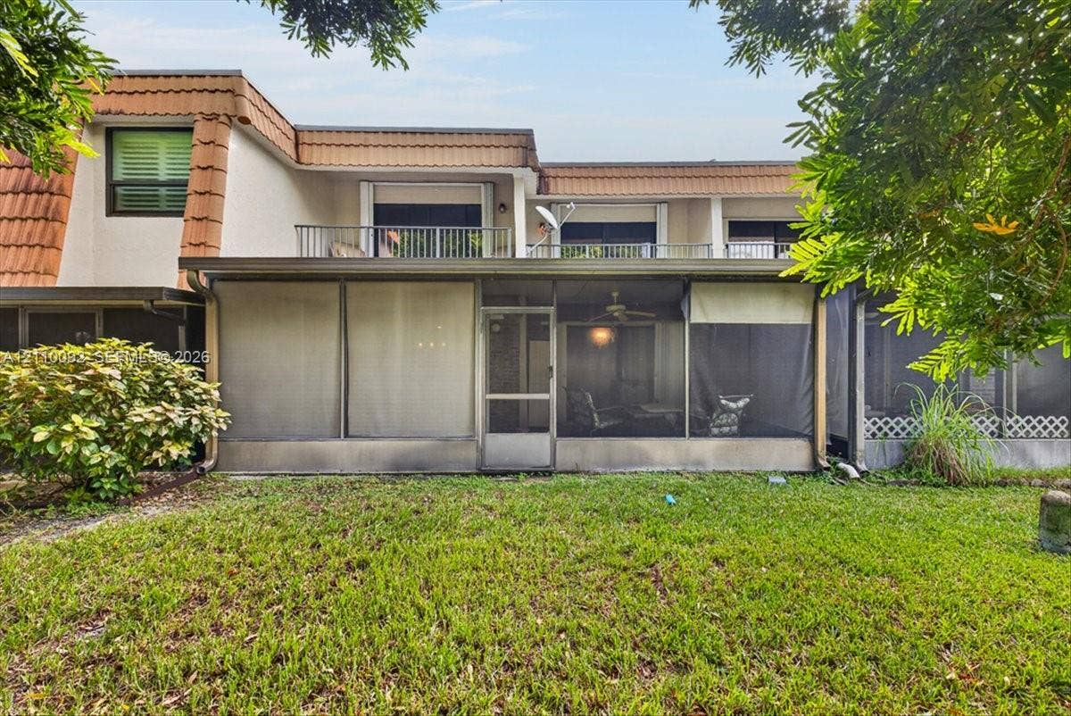 1403 SW 110th Way, Davie, FL 33324 Multi-level exterior featuring a screened-in ground floor patio, upper-level balcony with metal railing, stucco siding, and clay-tile roof detailing