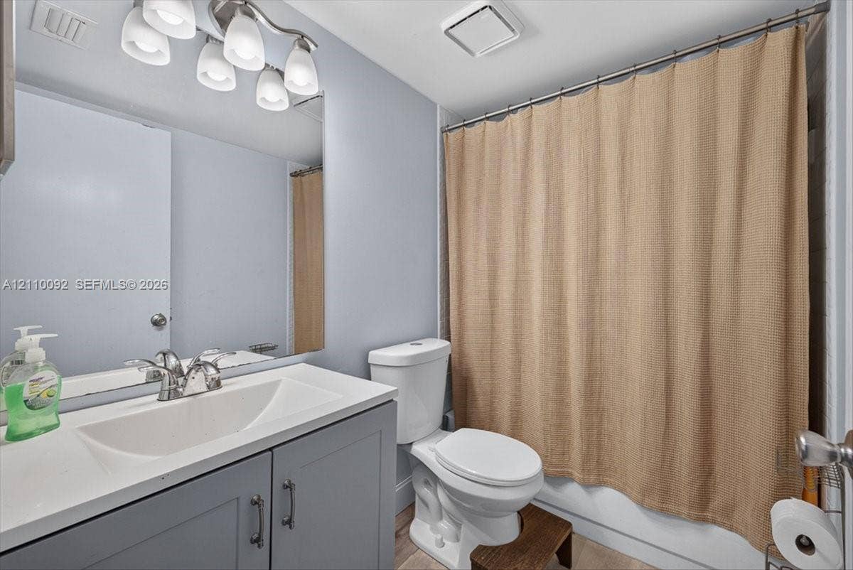 1403 SW 110th Way, Davie, FL 33324 Bathroom featuring a vanity with a white integrated basin, charcoal-toned cabinetry, a polished chrome faucet, and a multi-bulb light fixture above a wall-mounted mirror