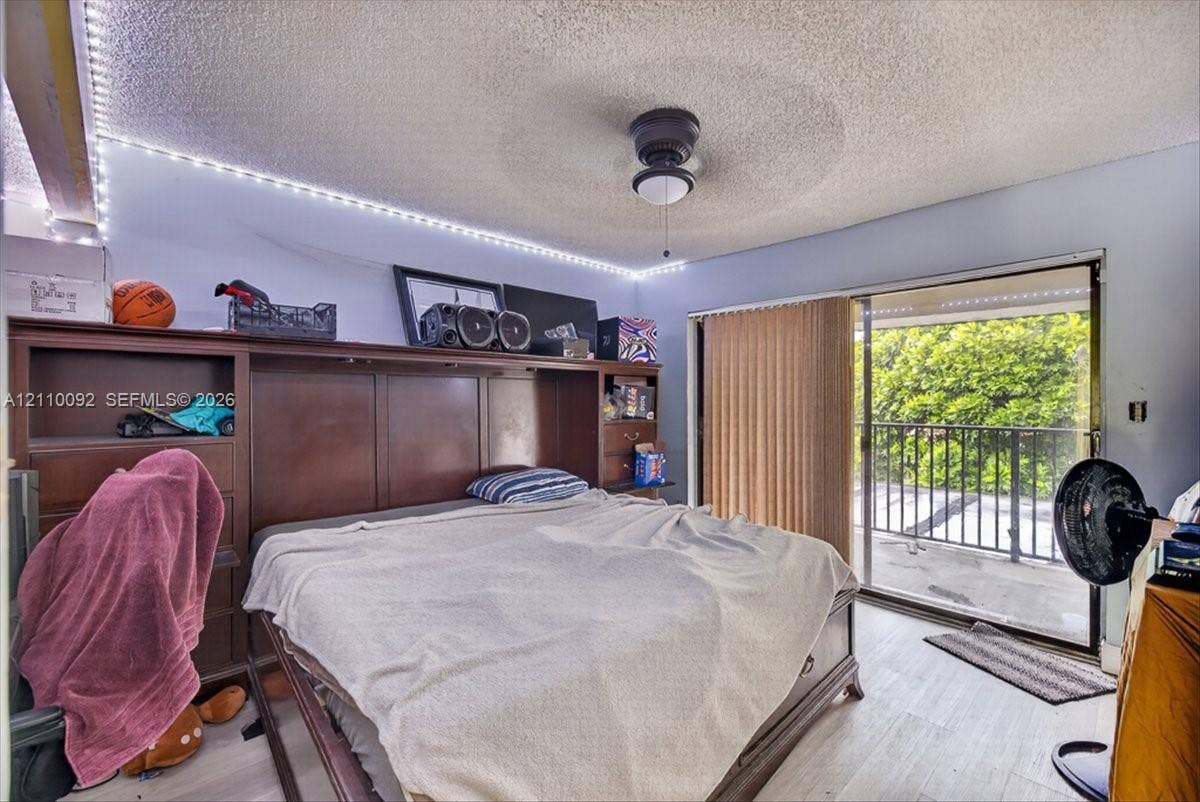 1403 SW 110th Way, Davie, FL 33324 Built-in wood cabinetry, ceiling fan, wood-finish flooring, and sliding glass door leading to a balcony