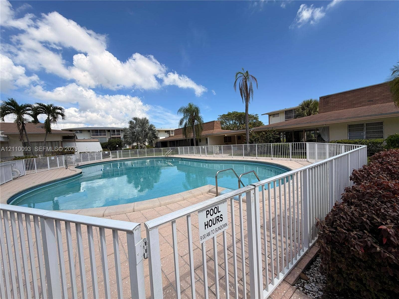 1395 NE 167th Street, #205, Miami, FL 33162 In-ground swimming pool featuring a concrete surround, metal perimeter fencing, and stainless steel pool ladder