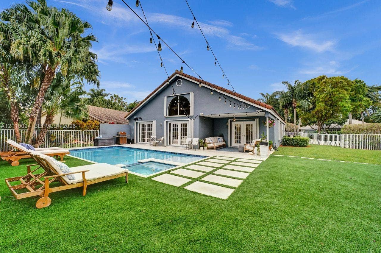 2064 Island Circle, Weston, FL 33326 Backyard featuring an in-ground swimming pool with integrated spa, paved stone walkway, covered patio, and perimeter fencing