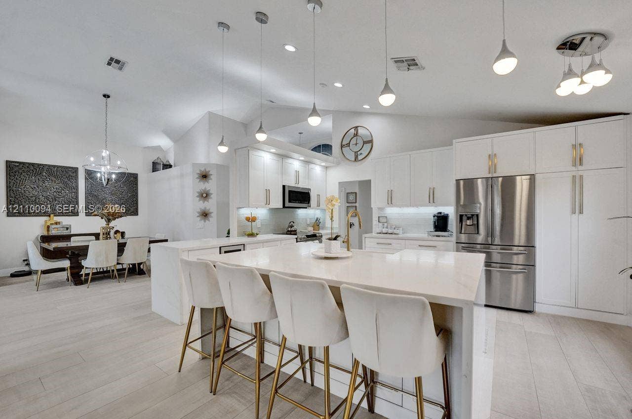 2064 Island Circle, Weston, FL 33326 Kitchen featuring white shaker cabinetry, a waterfall-edge center island with stone countertop, stainless steel appliances, recessed lighting, and wood-finish flooring