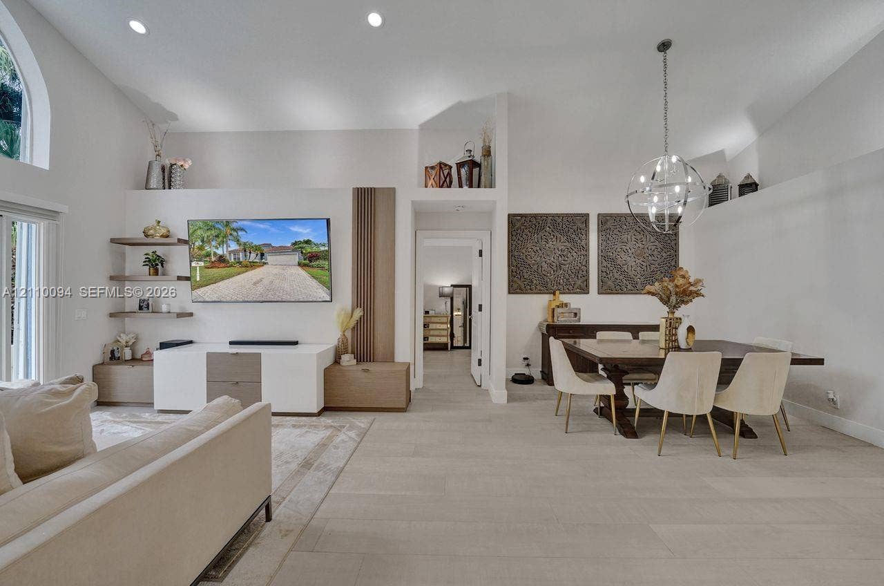 2064 Island Circle, Weston, FL 33326 Vaulted ceilings, custom wall-mounted shelving, integrated vertical wood-slat accent paneling, recessed lighting, and a modern spherical chandelier