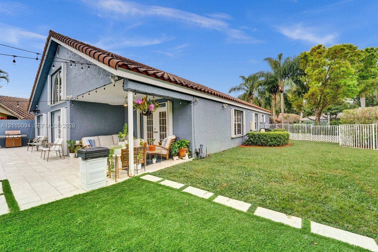 2064 Island Circle, Weston, FL 33326 Stucco exterior with a tiled roof, covered patio featuring paved hardscaping, and a fenced backyard with a manicured lawn