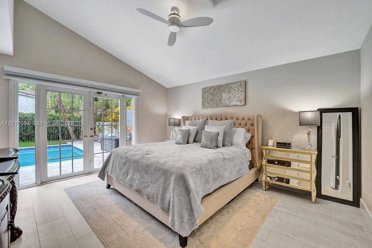2064 Island Circle, Weston, FL 33326 Vaulted ceilings, wood-finish flooring, and white-framed French doors opening to an exterior swimming pool