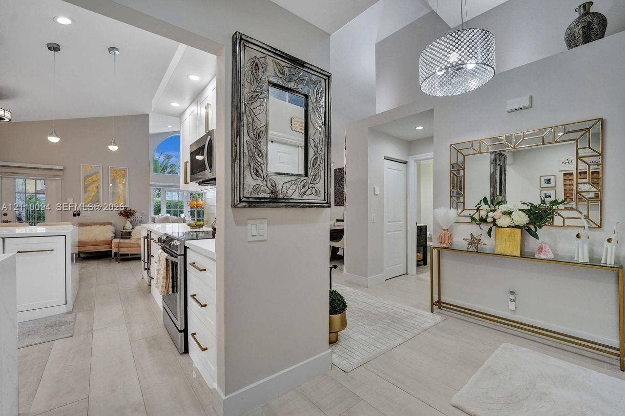 2064 Island Circle, Weston, FL 33326 Vaulted ceilings, wood-finish flooring, white shaker-style cabinetry, stainless steel appliances, and decorative recessed and pendant lighting