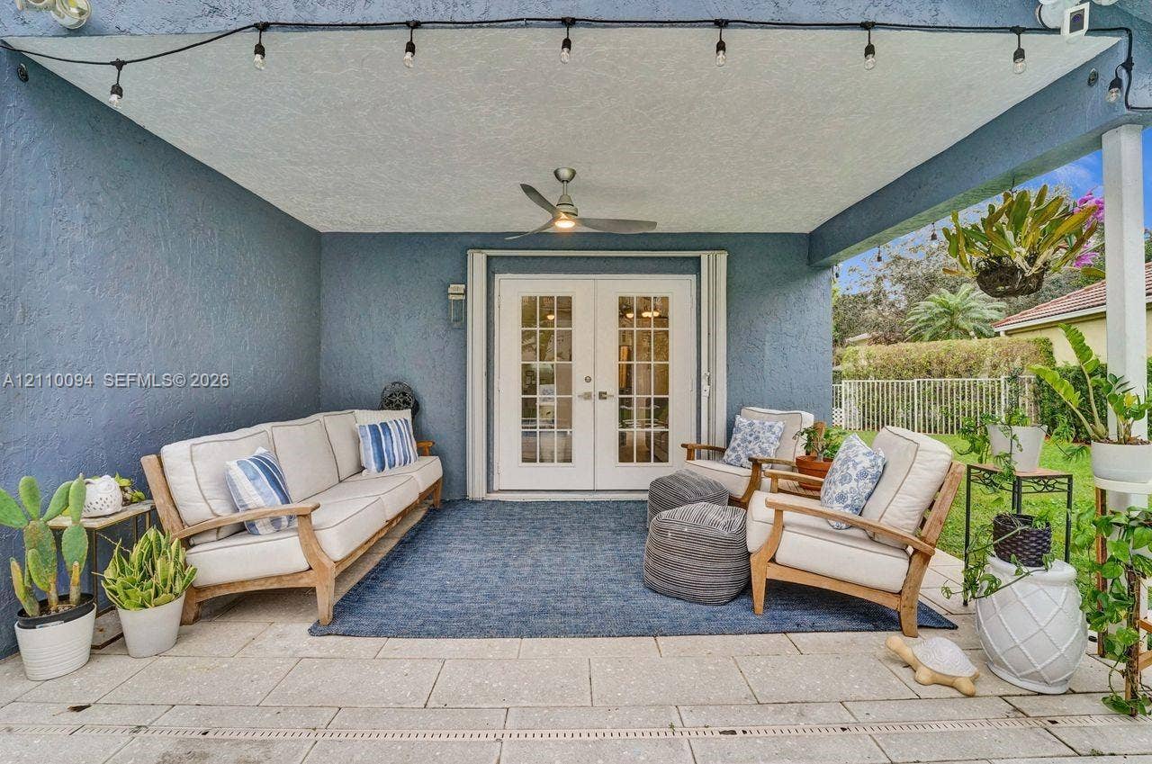 2064 Island Circle, Weston, FL 33326 Covered patio featuring stone-tiled flooring, white French doors, a central ceiling fan, and perimeter string lighting