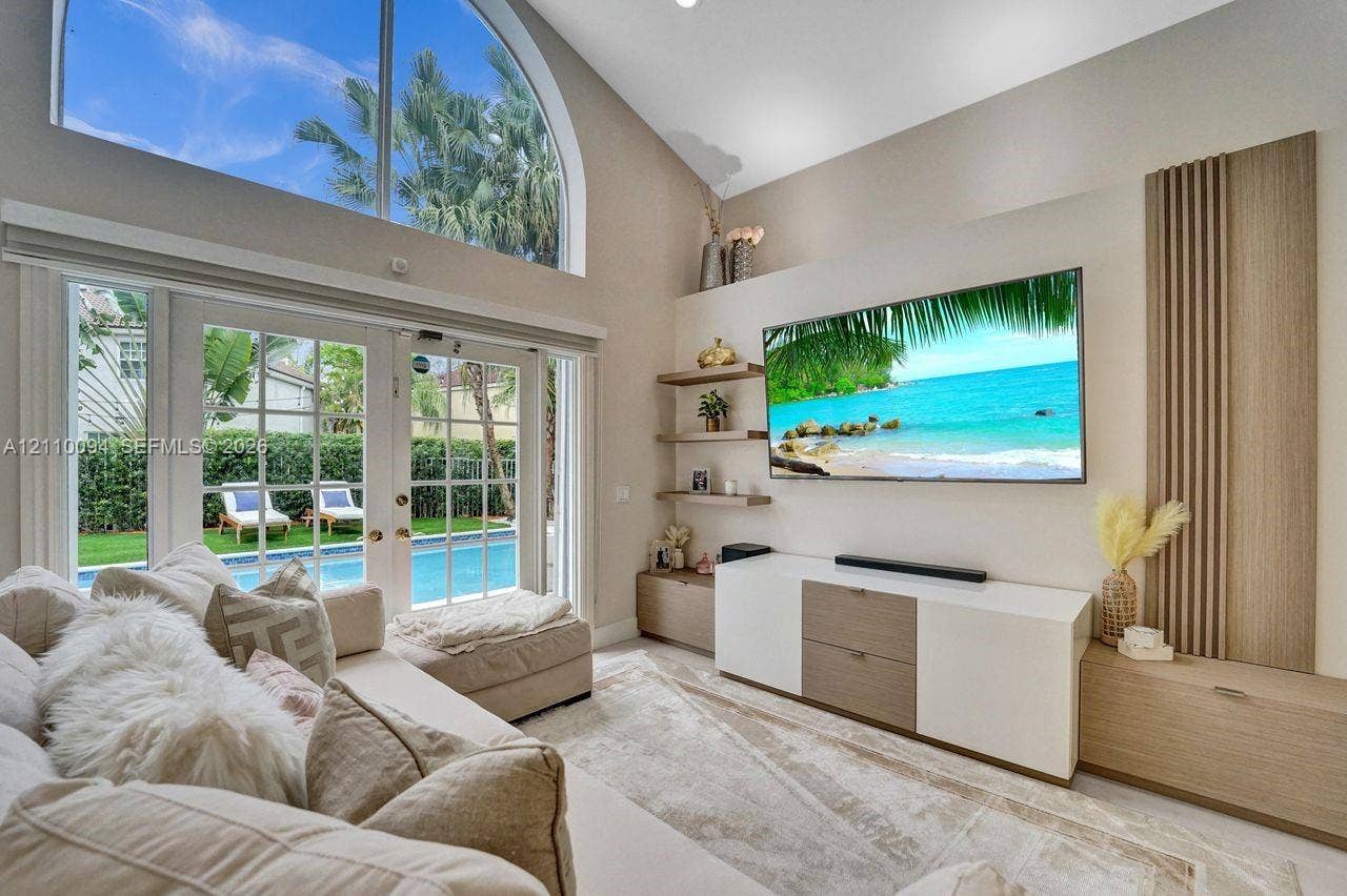 2064 Island Circle, Weston, FL 33326 Vaulted ceilings featuring an arched transom window, custom wood-slat wall paneling, built-in cabinetry, floating shelving, and French doors
