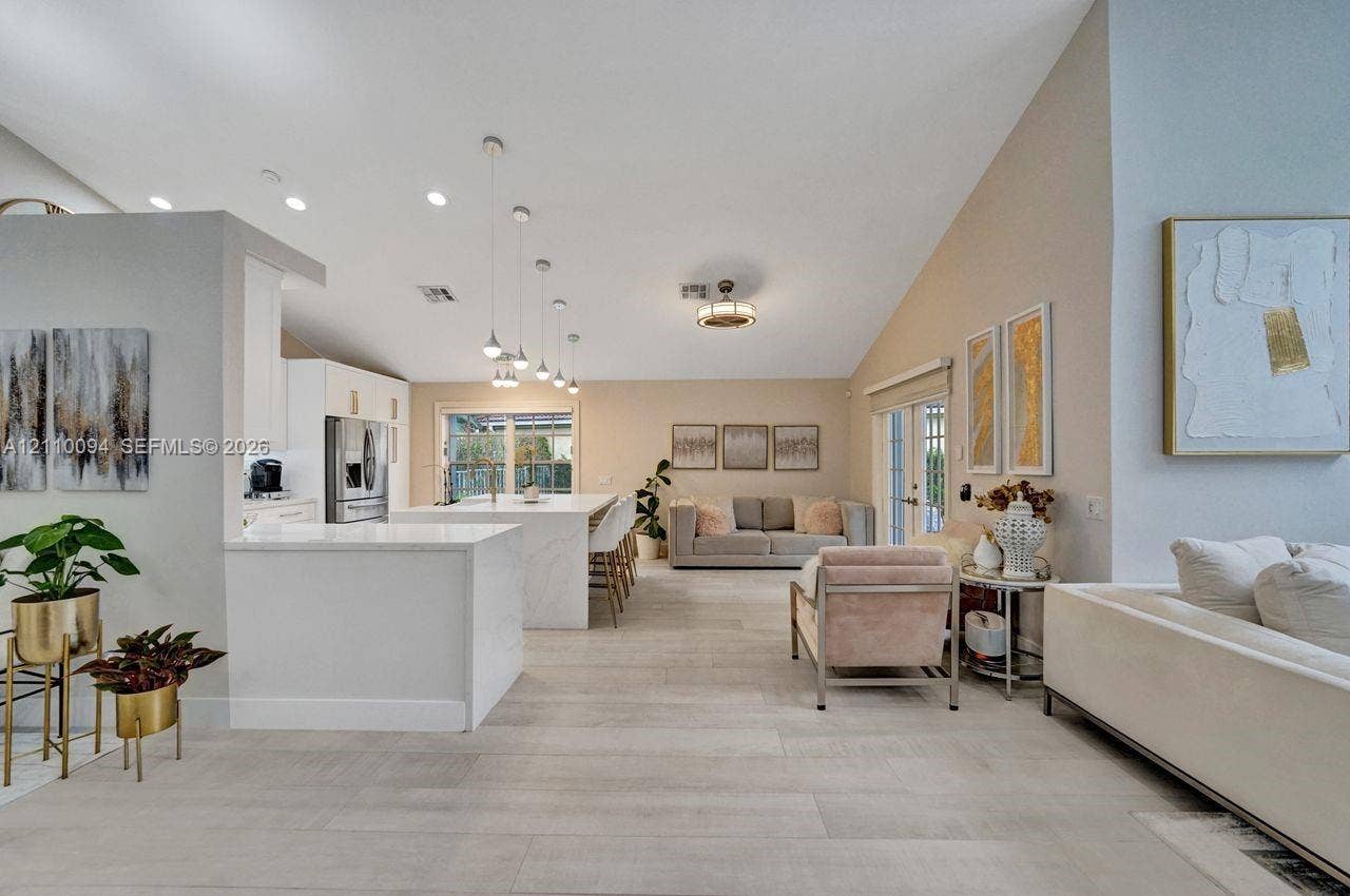 2064 Island Circle, Weston, FL 33326 Open-concept interior featuring vaulted ceilings, recessed lighting, wood-finish flooring, a kitchen island with stone-style countertops, and pendant lighting