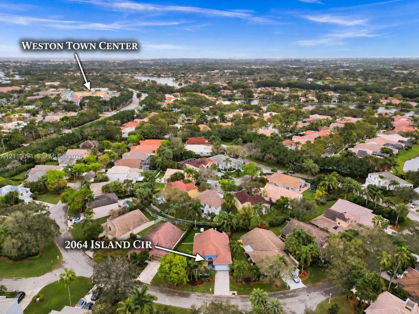 2064 Island Circle, Weston, FL 33326 Aerial perspective of a single-family residence featuring a tiled roof and concrete driveway, situated within a suburban neighborhood with mature trees and proximity to Weston Town Center