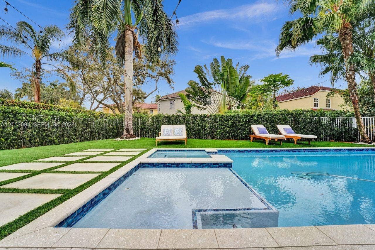 2064 Island Circle, Weston, FL 33326 In-ground swimming pool with an integrated spa, stone-paver decking, manicured lawn, and perimeter privacy hedging