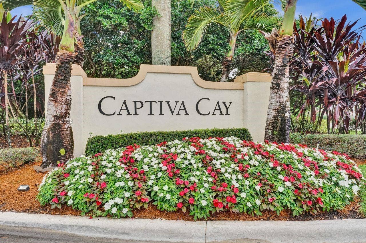 2064 Island Circle, Weston, FL 33326 Stucco monument signage featuring professional lettering surrounded by manicured tropical landscaping, palm trees, and colorful floral beds