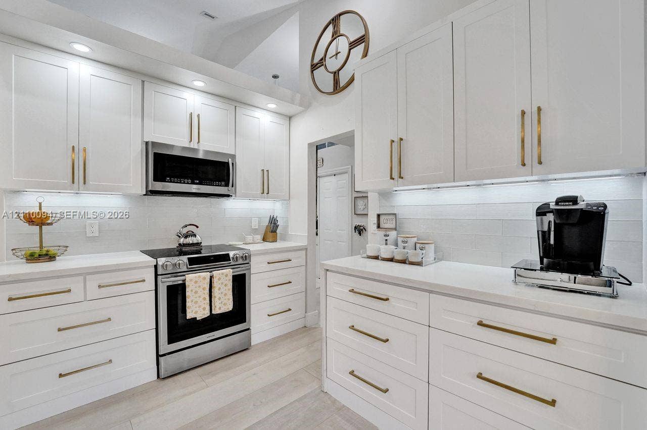 2064 Island Circle, Weston, FL 33326 Kitchen featuring white shaker-style cabinetry, quartz countertops, subway tile backsplash, stainless steel appliances, and brushed brass hardware