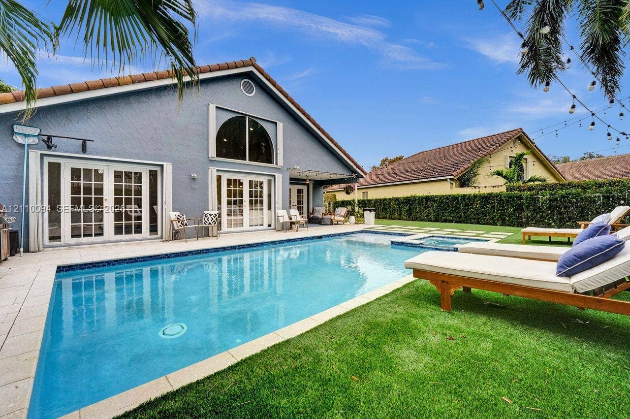 2064 Island Circle, Weston, FL 33326 Stucco exterior featuring a multi-pane glass door entry, an in-ground swimming pool with an integrated spa, and a concrete patio