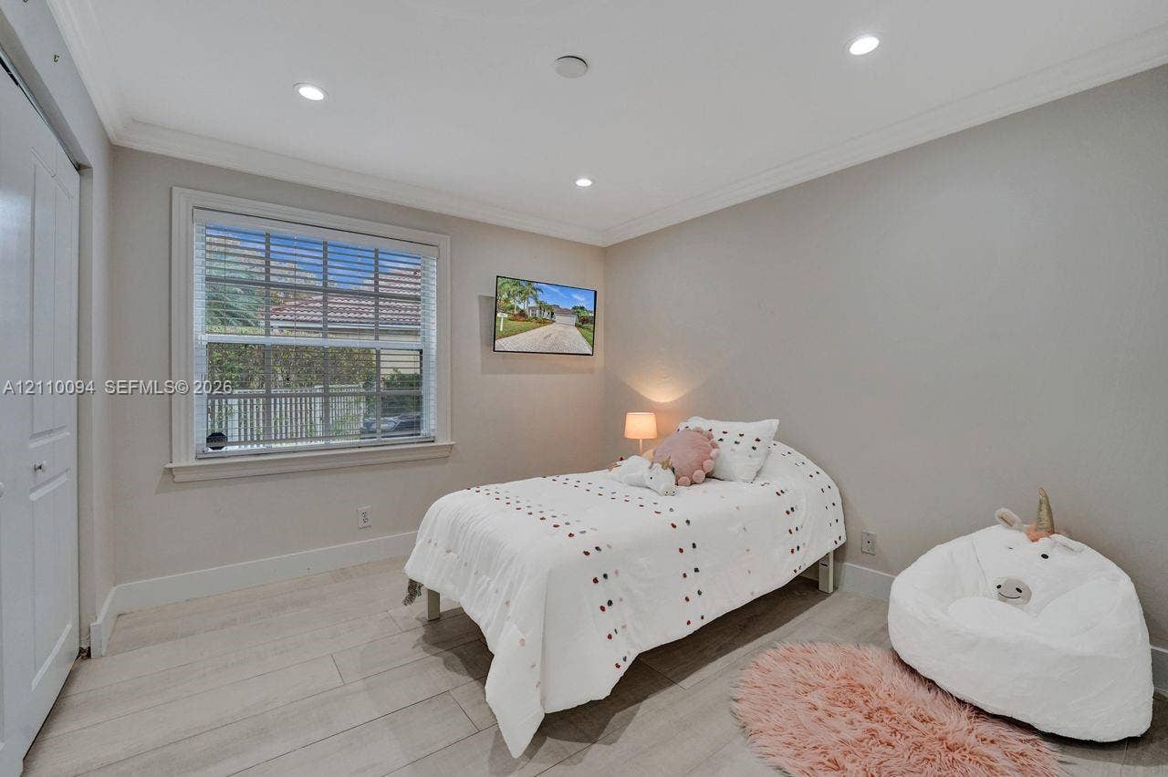 2064 Island Circle, Weston, FL 33326 Neutral-toned bedroom featuring wood-finish flooring, recessed lighting, crown molding, and a multi-pane window with white blinds