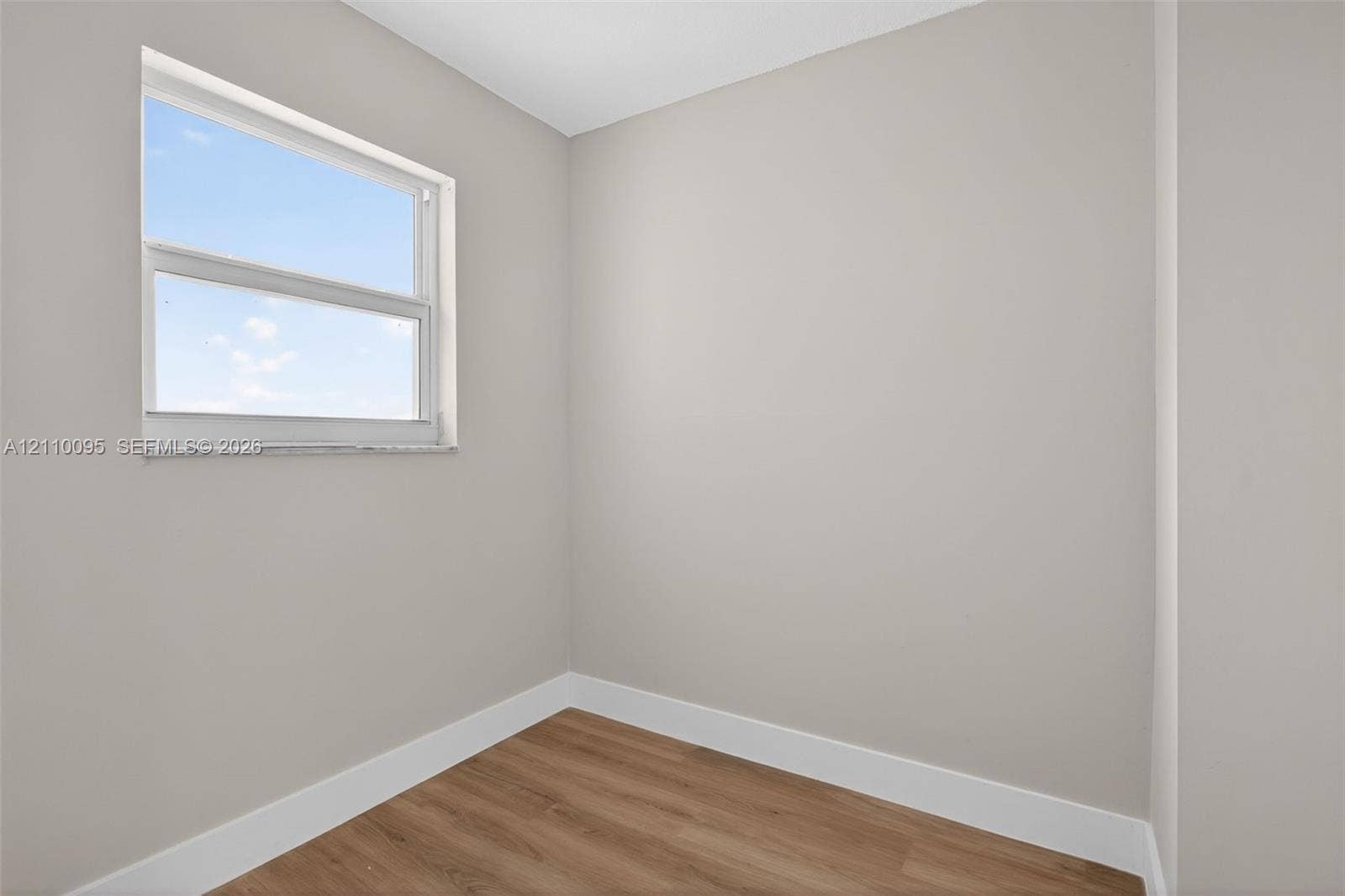 3090 N Course Drive, #807, Pompano Beach, Pompano Beach, FL 33069 Neutral-toned interior space featuring wood-finish flooring and a single window with a stone sill