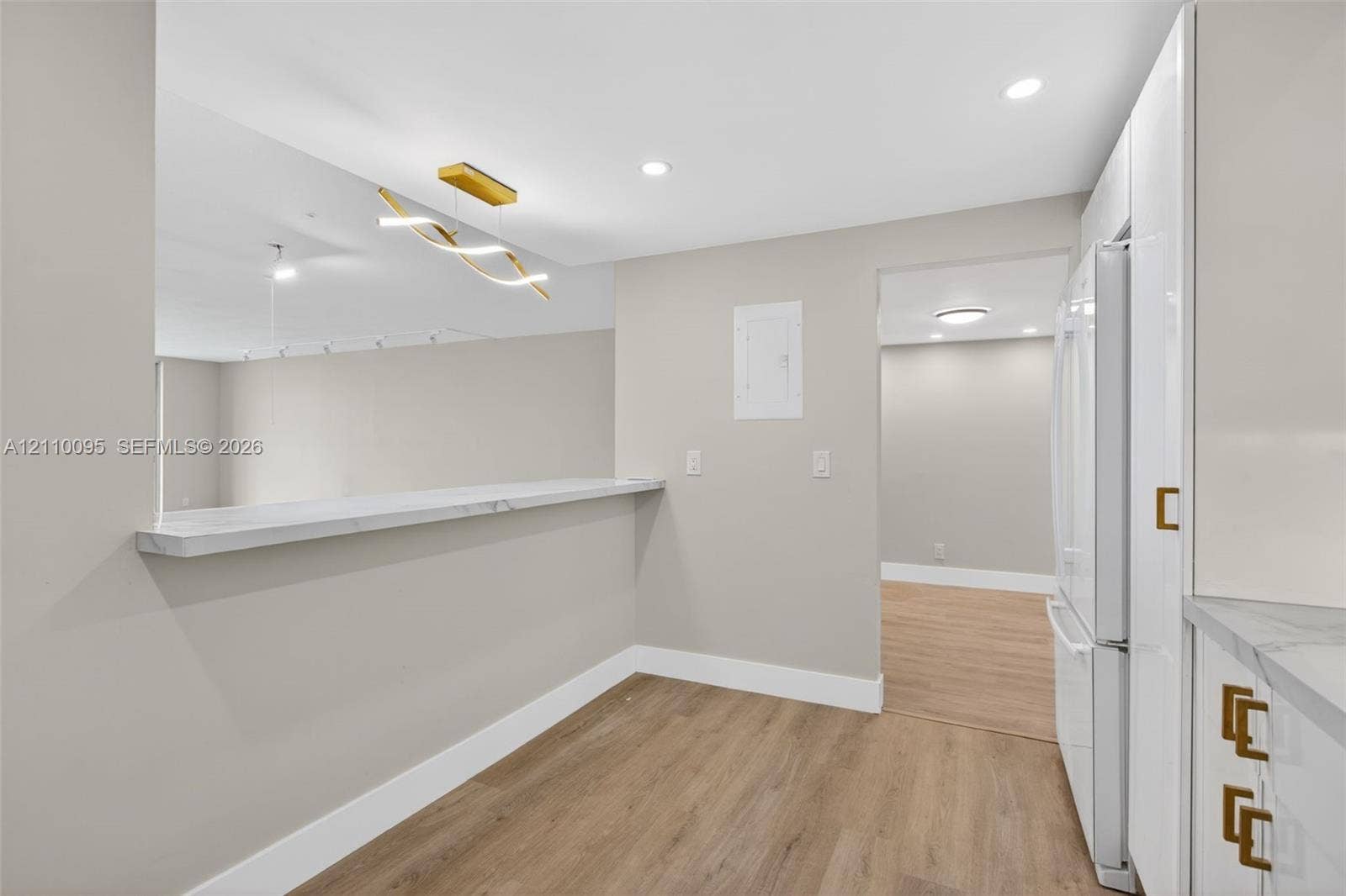 3090 N Course Drive, #807, Pompano Beach, Pompano Beach, FL 33069 Kitchen featuring white cabinetry with gold-tone hardware, stone-finish countertops, wood-finish flooring, recessed lighting, and a modern sculptural pendant fixture