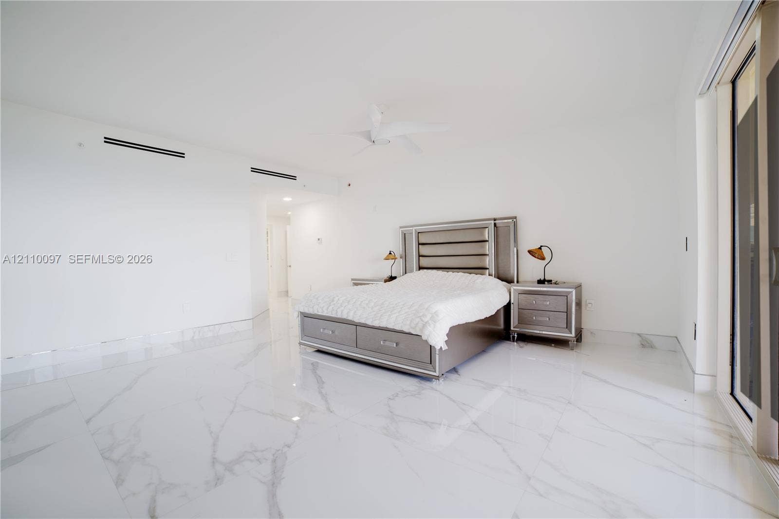 Polished large-format stone flooring featuring prominent veining, white wall finishes, and a ceiling-mounted fan