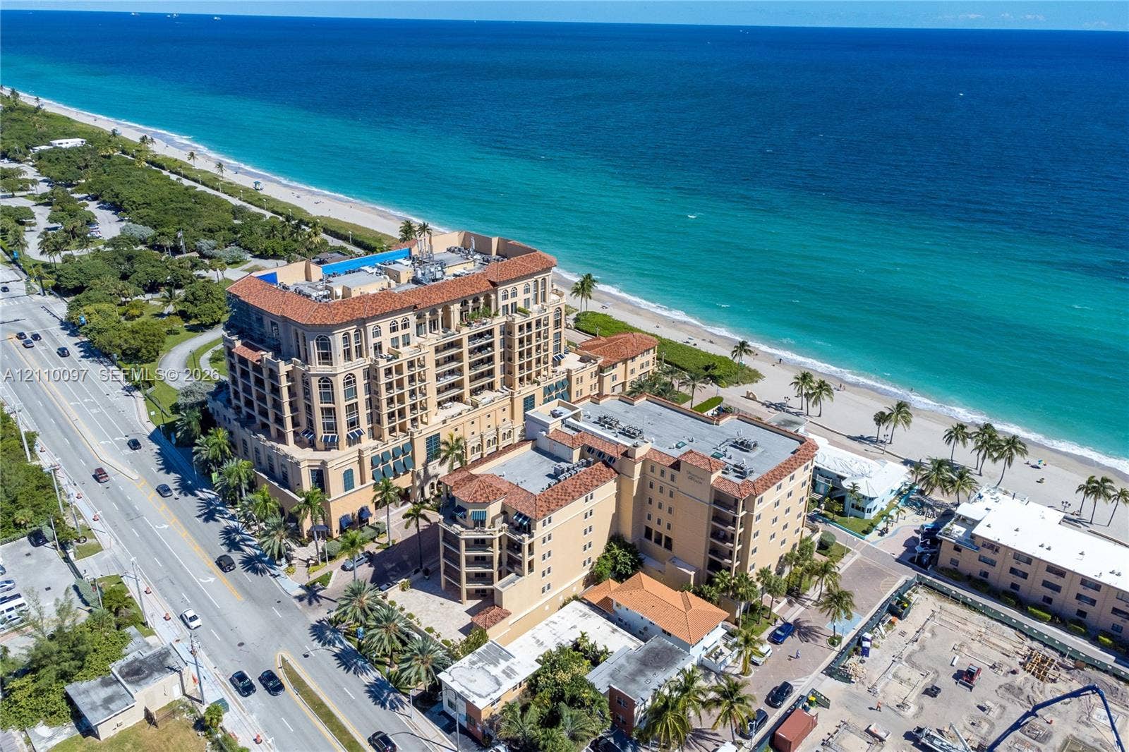 High-rise coastal property featuring Mediterranean-inspired architectural design, terracotta tile roofing, multi-level balconies, and a direct beachfront location