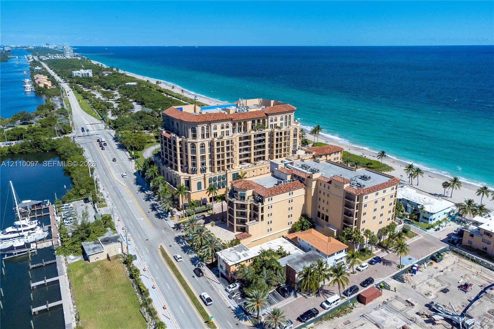 Multi-story masonry building with terracotta tile roof, recessed balconies, and direct proximity to the ocean and coastline