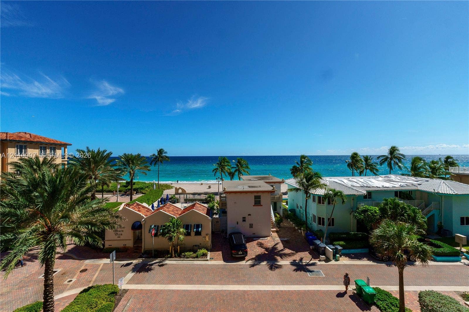 Oceanfront exposure featuring panoramic horizon scenery, paved brick pedestrian pathways, mature palm trees, and coastal access