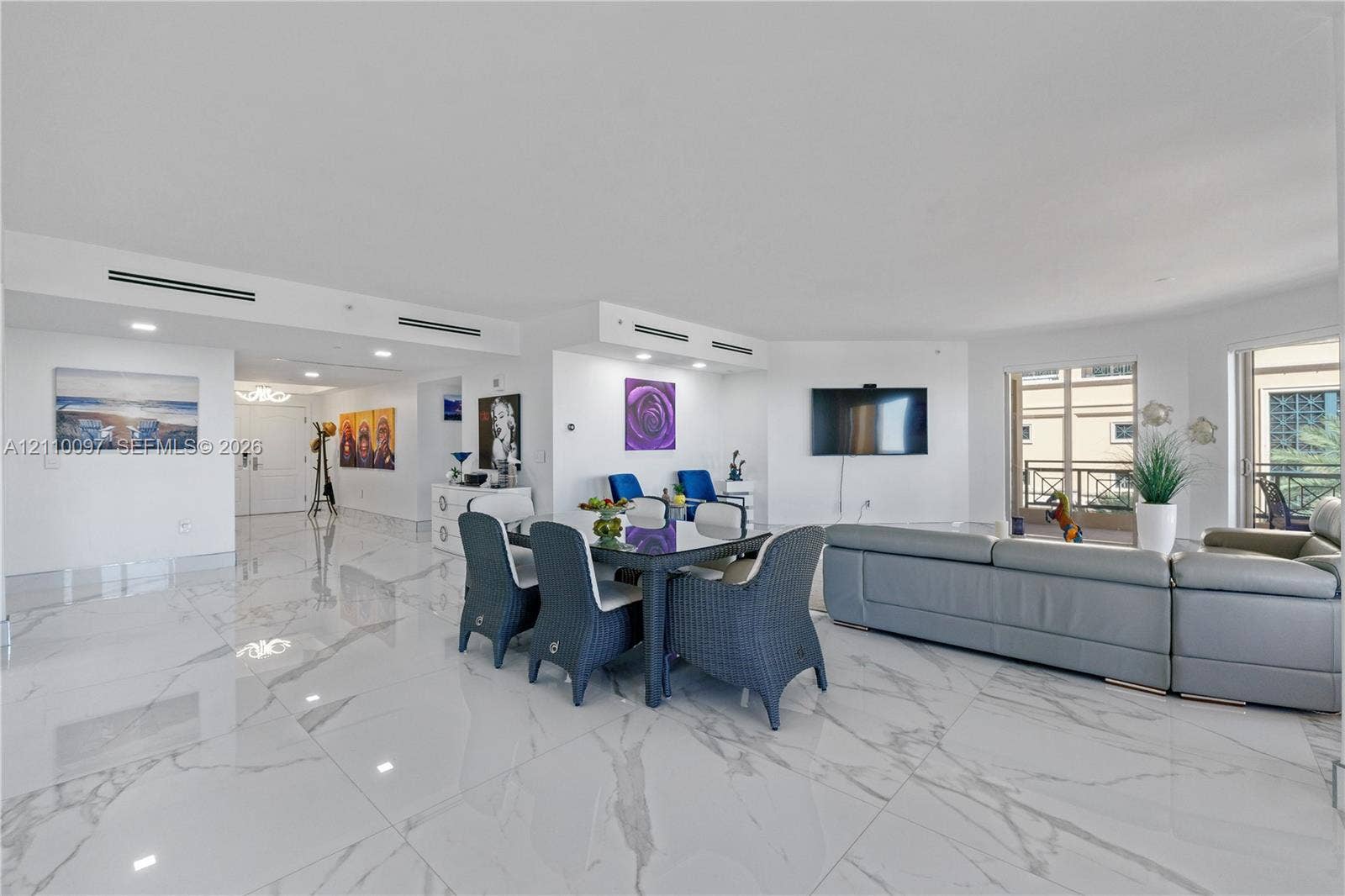 Open-concept interior featuring large-format polished stone-finish flooring, recessed lighting, integrated ceiling linear air registers, and floor-to-ceiling glass door access to a balcony
