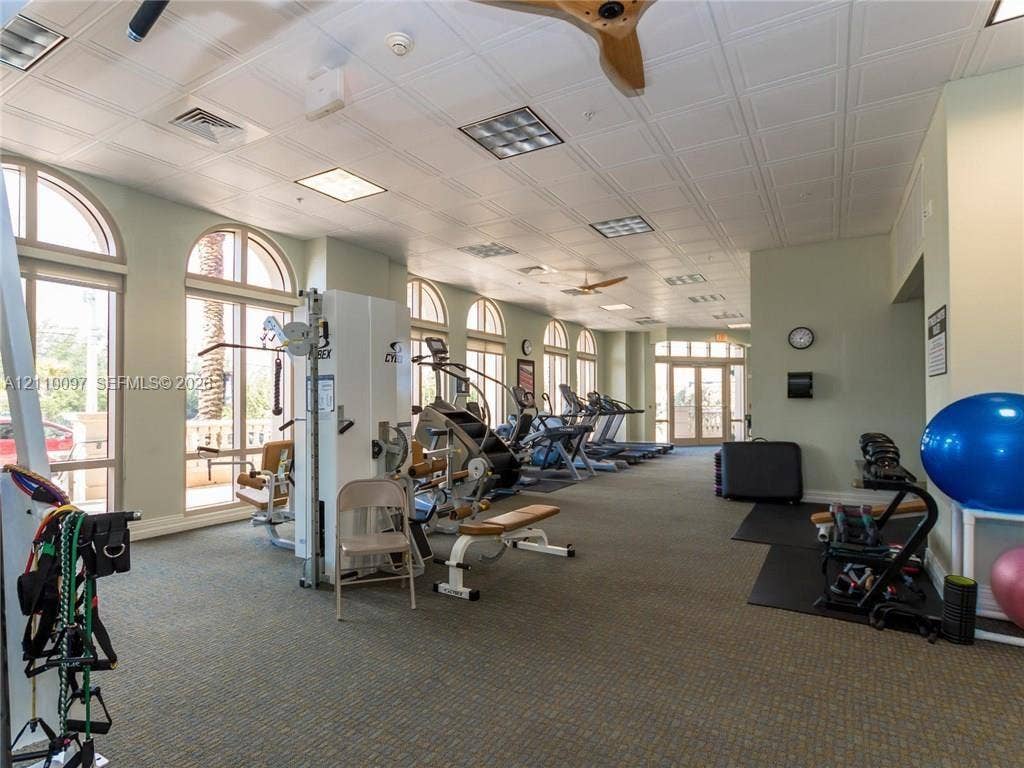 Fitness center featuring arched windows, paneled ceiling, recessed lighting, and integrated ceiling fans