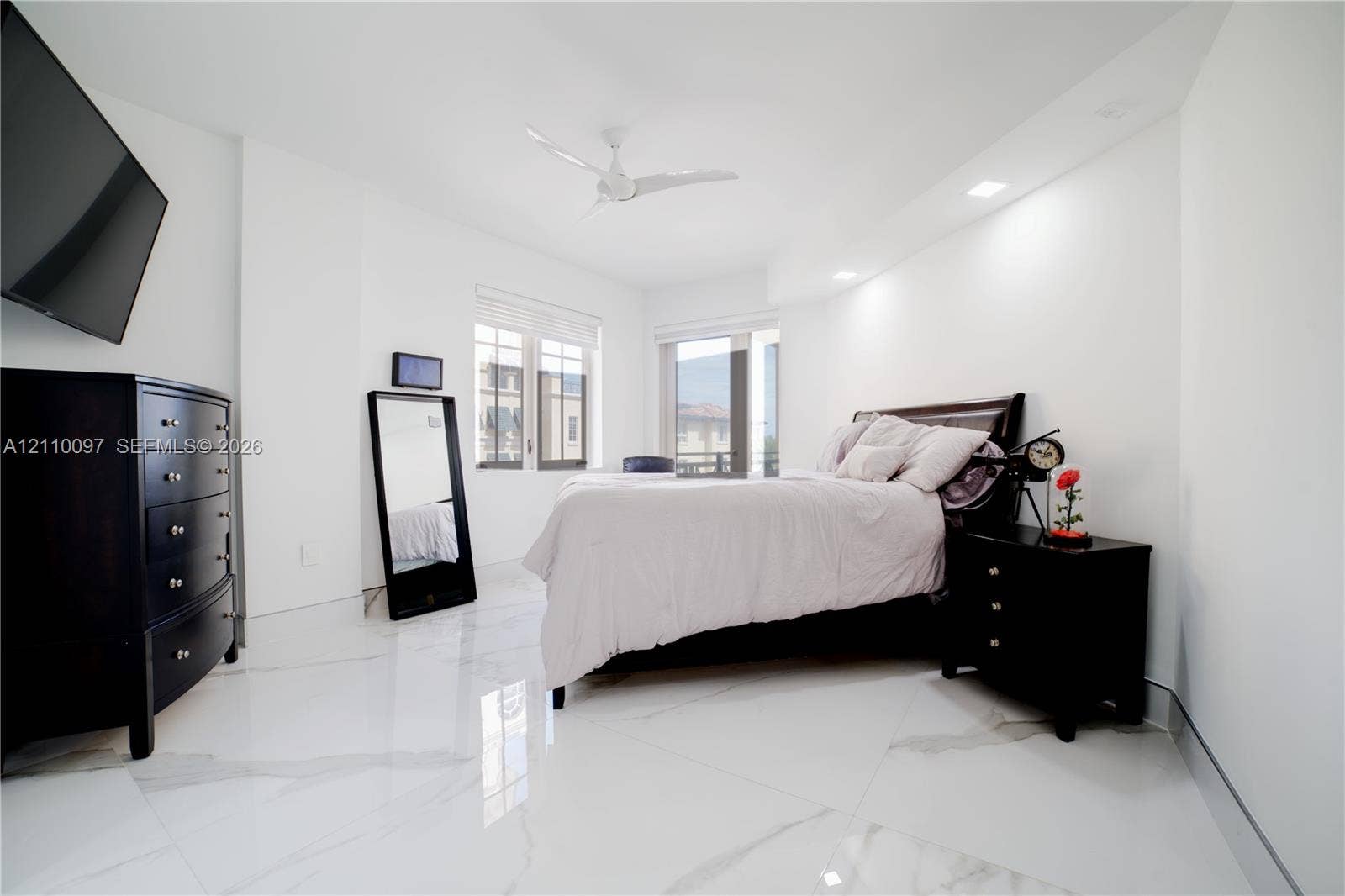 Large-format stone tile flooring, recessed ceiling lighting, and a white multi-blade ceiling fan
