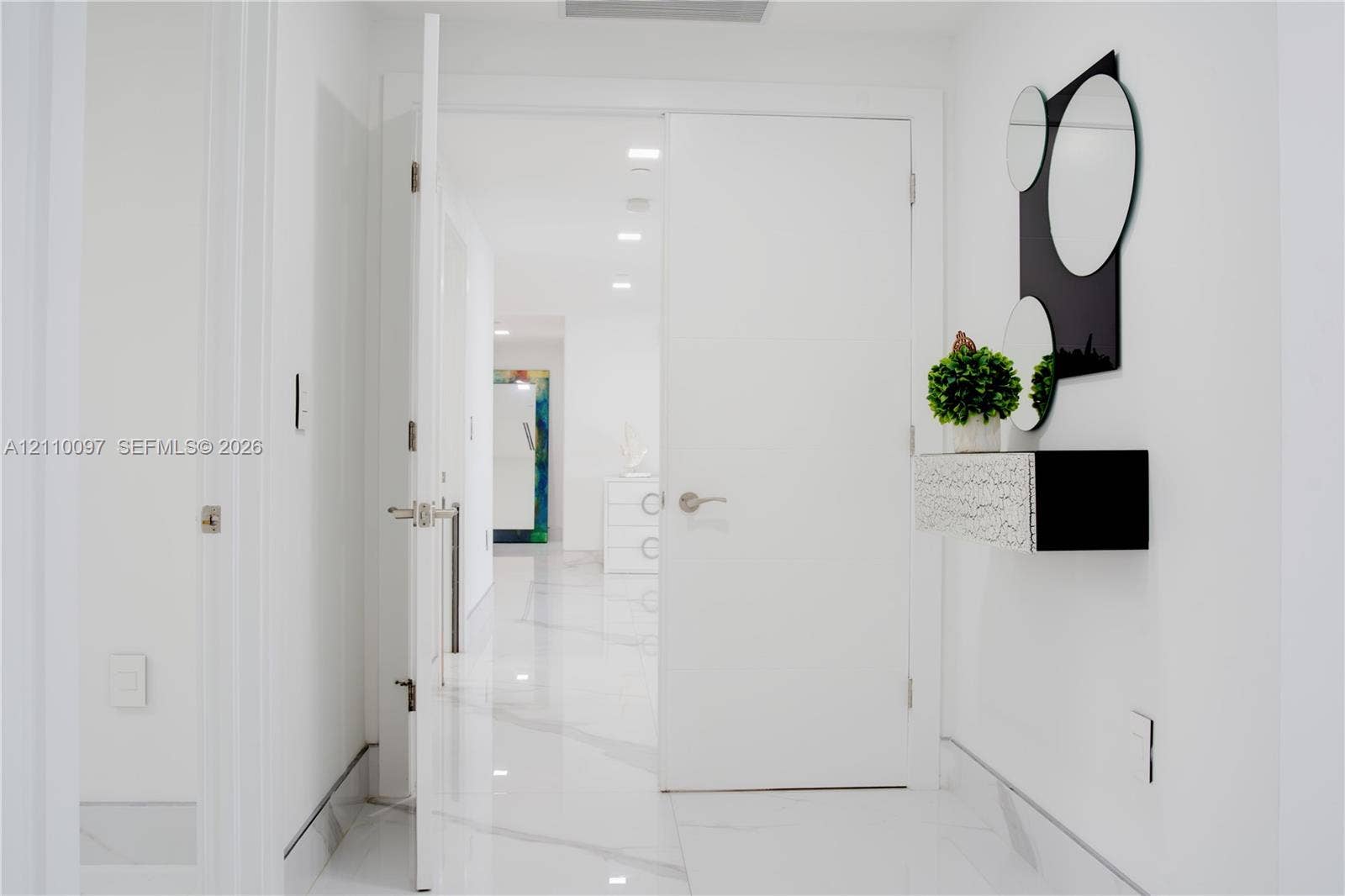 Interior hallway featuring large-format white veined flooring and recessed ceiling lighting
