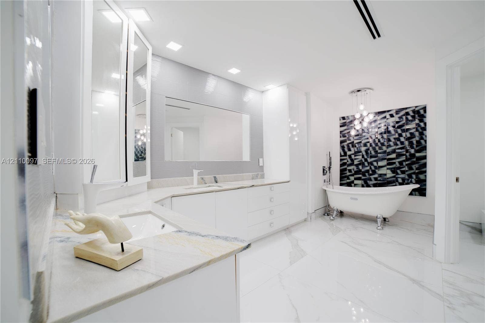 Bathroom featuring a white clawfoot tub, custom built-in cabinetry with stone countertops, large-format tile flooring, recessed ceiling lighting, and a multi-pendant light fixture