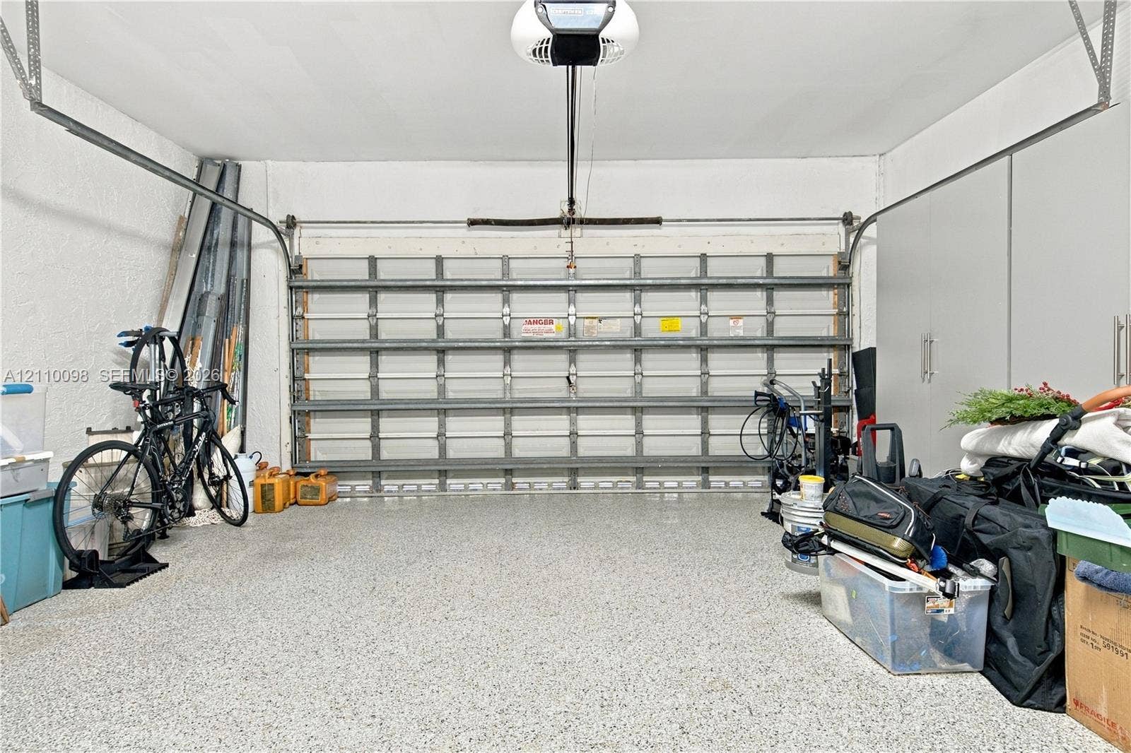 Two-car garage featuring a sectional metal door, epoxy-coated concrete flooring, and ceiling-mounted automatic door opener